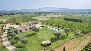 Una villa con piscina, rodeada de viñedos y montañas al fondo.