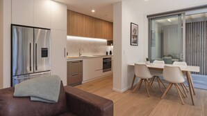 Een moderne keuken met roestvrijstalen apparatuur, een houten aanrecht en een eethoek met tafel en stoelen.