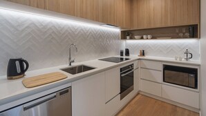 Een moderne keuken met een backsplash van visgraat tegels, roestvrijstalen apparatuur en houten keukenkastjes.