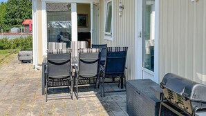 Une terrasse extérieure avec un barbecue, deux chaises et une table.