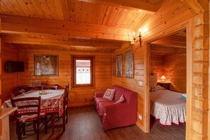 A cozy log cabin interior with a dining area, a sofa, and a bed.