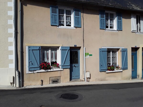 Ein Gebäude mit blauen Fensterläden, Hausnummer 7, und Blumenkästen an den Fensterbänken.