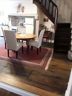 Ein Essbereich mit einem Holztisch, vier Stühlen, einem roten Teppich und einer Treppe zu einer oberen Ebene.