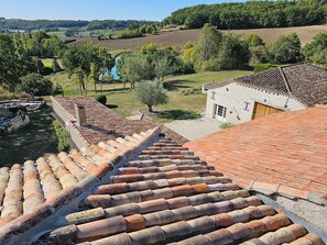 A traditional building with a terracotta roof, a stone wall, and a small garden area.