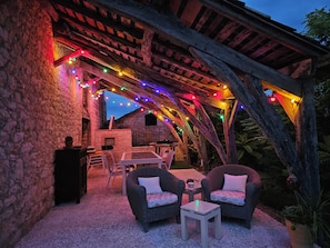 An outdoor patio with stone walls, wooden beams, and string lights.