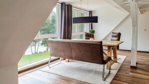 Un comedor moderno con una mesa de madera, sillas tapizadas en tono café y una lámpara colgante.