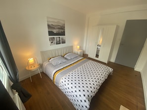 Un dormitorio con cama, lámparas de noche, armario y un cuadro en la pared.