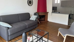 Uma sala de estar moderna com um sofá cinzento, uma mesa de centro de vidro e uma parede de destaque vermelha.