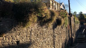 A stone wall with a wooden fence and a building with a sloped roof. - Stunning views, period town house, central Dartmouth close to river, quiet road. (Dartmouth)