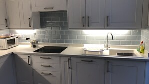 A modern kitchen with grey cabinets, a white countertop, a microwave, a sink, and a dish rack. - Stunning views, period town house, central Dartmouth close to river, quiet road. (Dartmouth)