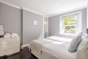 Quarto com cama, penteadeira, janela e espelho.