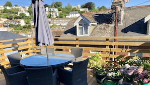 A wooden deck with a round table and chairs, surrounded by potted plants and a wooden fence. - Stunning views, period town house, central Dartmouth close to river, quiet road. (Dartmouth)