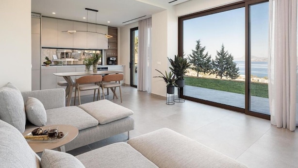 A modern living room with a sofa, a dining table with chairs, and a kitchen area in the background.