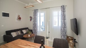 Ett modernt vardagsrum med ett matbord i trä, en svart soffa och en platt-TV som är monterad på väggen.