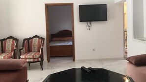 A room with a bed, two armchairs, a television, and a coffee table. - Belgium district (Tanger)