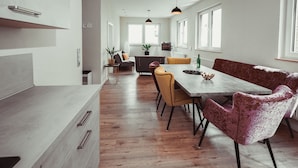 Eine moderne Küche mit einer langen Arbeitsplatte, Holzboden und einem Essbereich mit einer Bank und Stühlen.