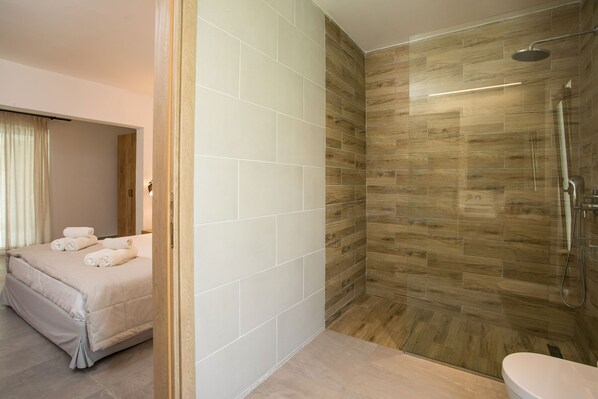 Ein modernes Badezimmer mit Dusche, Toilette und einem Bett mit Handtüchern.