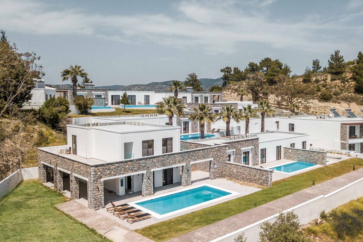 Un complexe hôtelier moderne composé de plusieurs bâtiments, chacun doté d’une piscine et agrémenté d’éléments décoratifs en pierre.