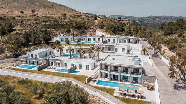 A modern resort with multiple buildings, swimming pools, and palm trees.