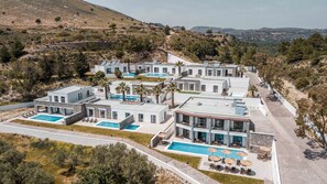 Ein modernes Resort mit mehreren Gebäuden, Schwimmbecken und Palmen.