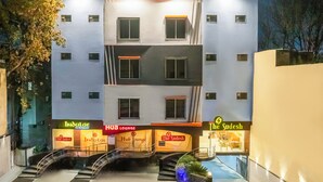 A multi-story hotel with balconies, a central staircase, and signage for 'Indulge' and 'Hub Lounge'. - HOTEL THE SUDESH (Raipur)