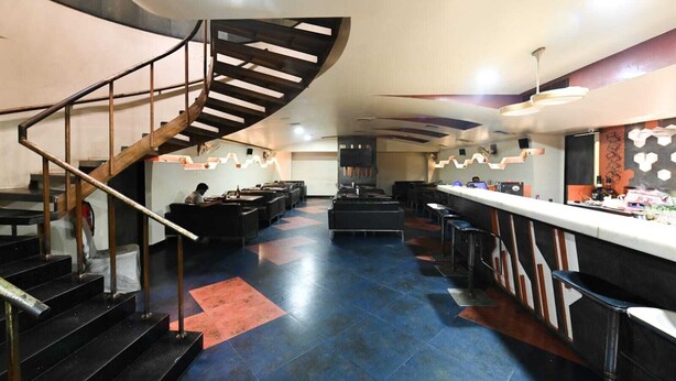 A modern restaurant with a spiral staircase, seating area, and bar. - HOTEL THE SUDESH (Raipur)