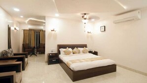 A modern hotel room with a large bed, bedside tables, a desk, and a chair. - HOTEL THE SUDESH (Raipur)