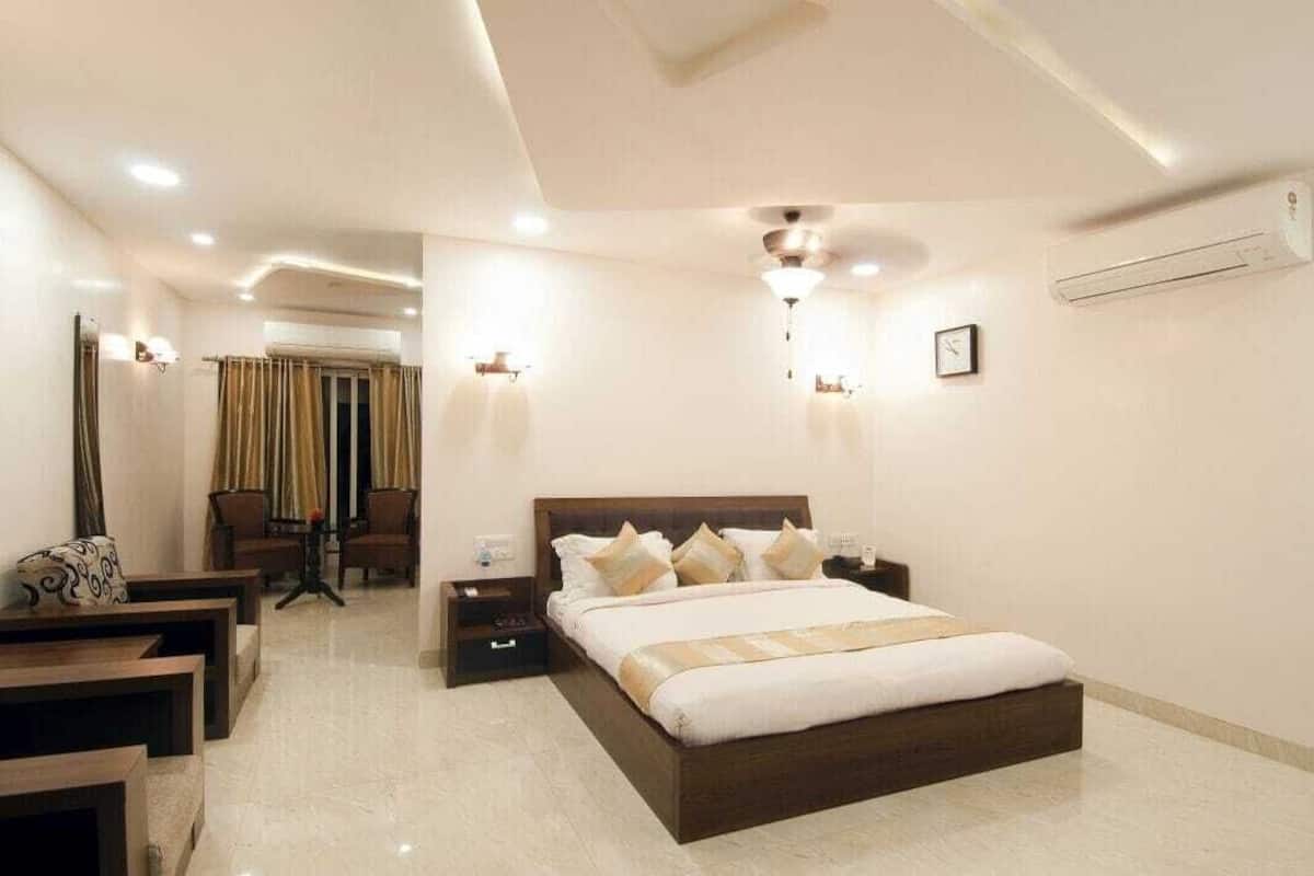 A modern hotel room with a large bed, bedside tables, a desk, and a chair.