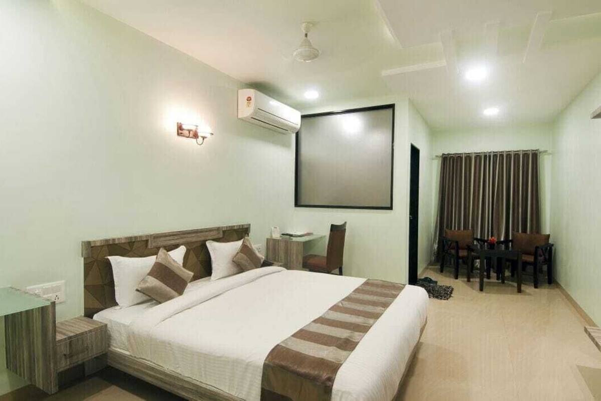 A hotel room with a bed, bedside table, desk, and chairs.