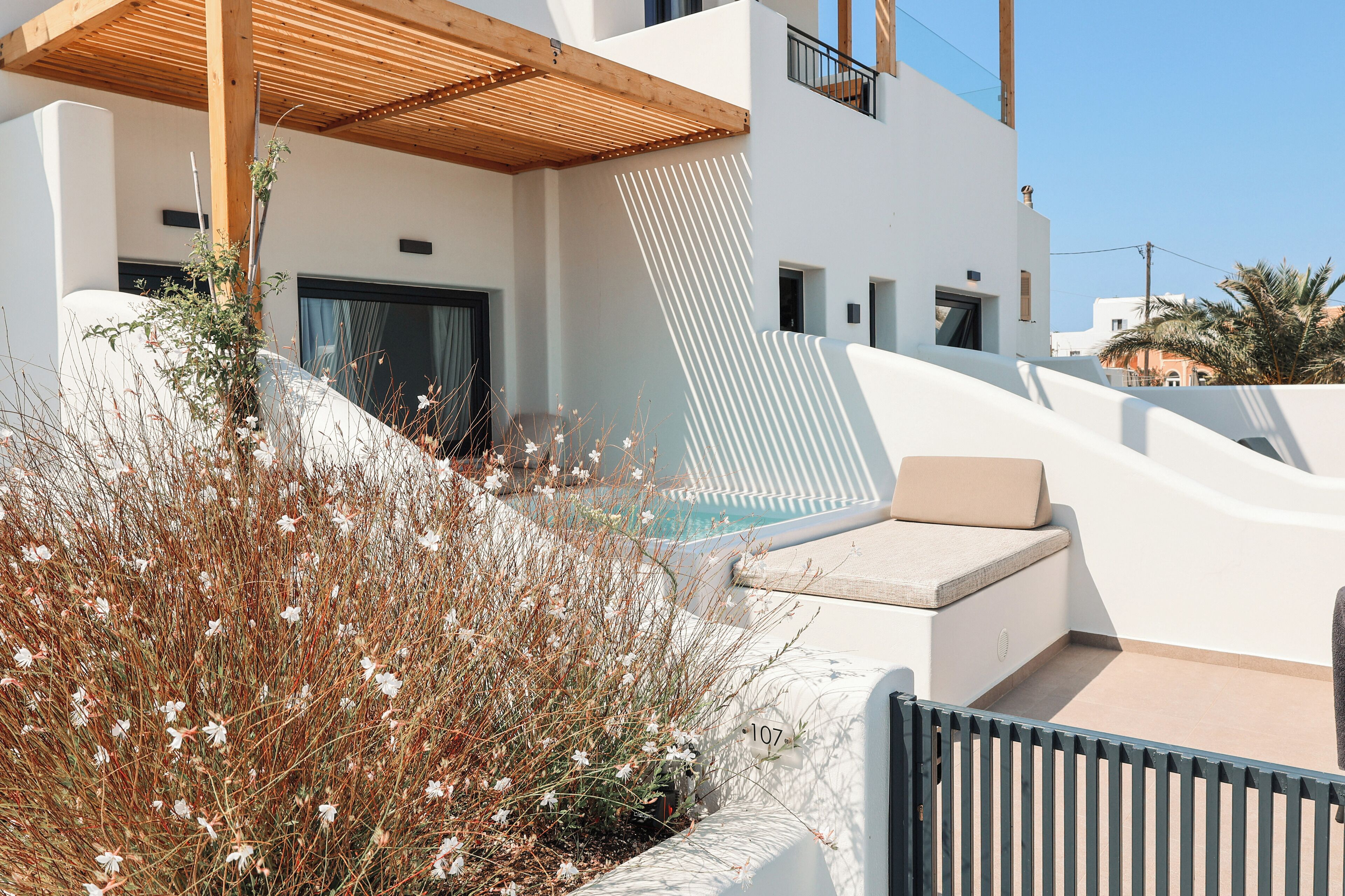 Un edificio moderno con piscina, mobiliario exterior y jardín.