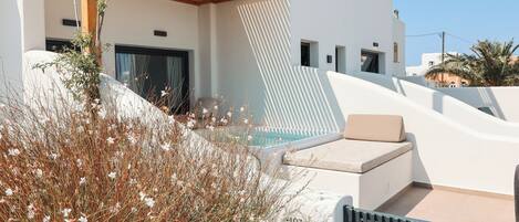 Un edificio moderno con piscina, mobiliario exterior y jardín.