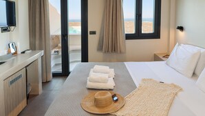 Habitación de hotel con cama, escritorio con computadora, televisor y vista al desierto por la ventana.