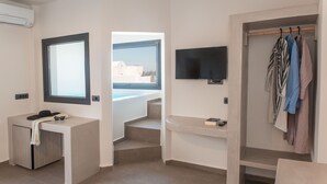 Una habitación de hotel moderna con un ventanal grande, un televisor de pantalla plana, un escritorio con teléfono y un perchero.