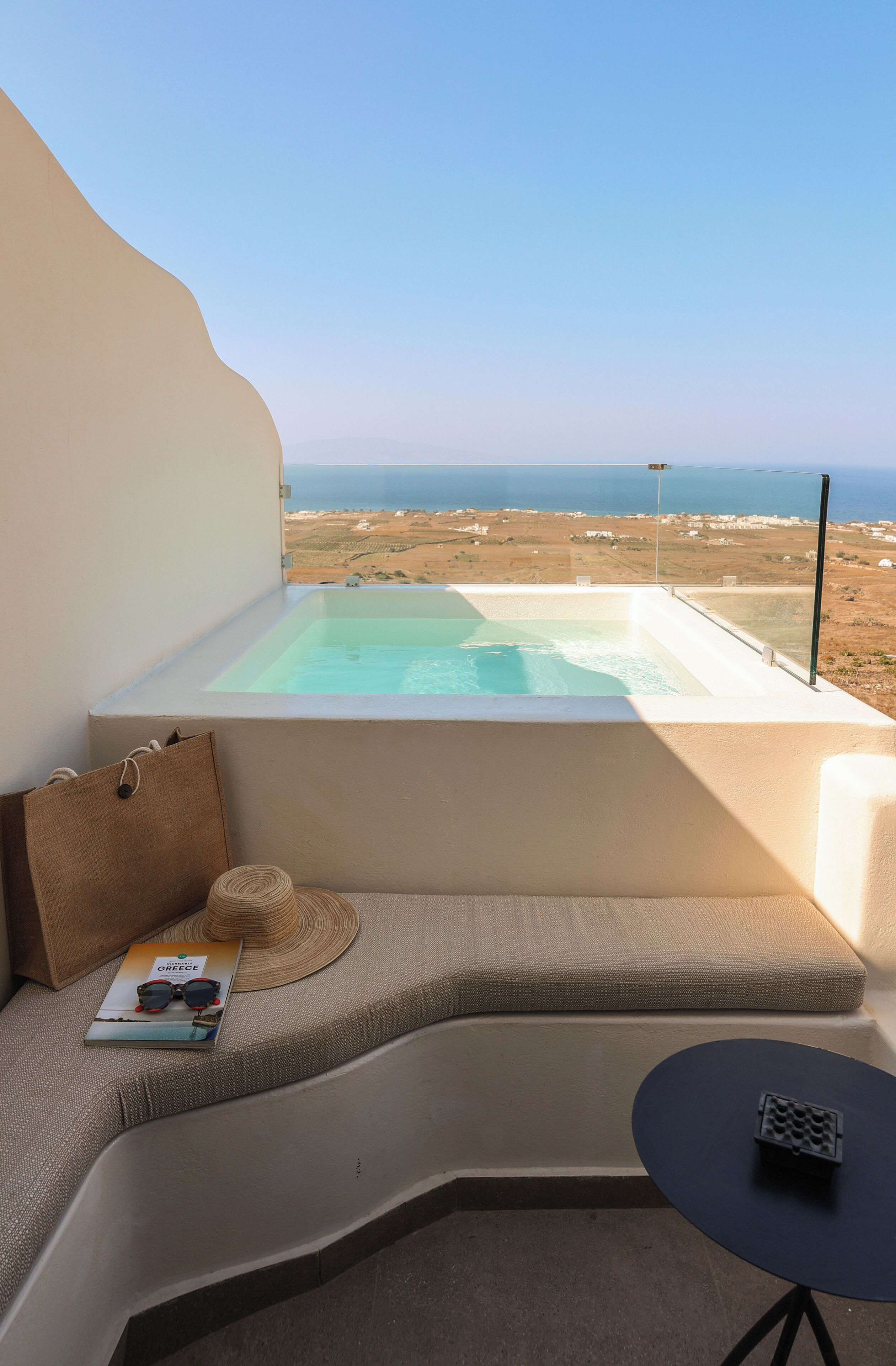 A modern room with a built-in hot tub, a sofa, a small table, and a view of the sea.
