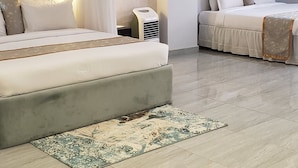 A modern bedroom with a large bed, a smaller bed, a bedside table, and a ceiling fan. - The Voice Hotel (Entebbe)