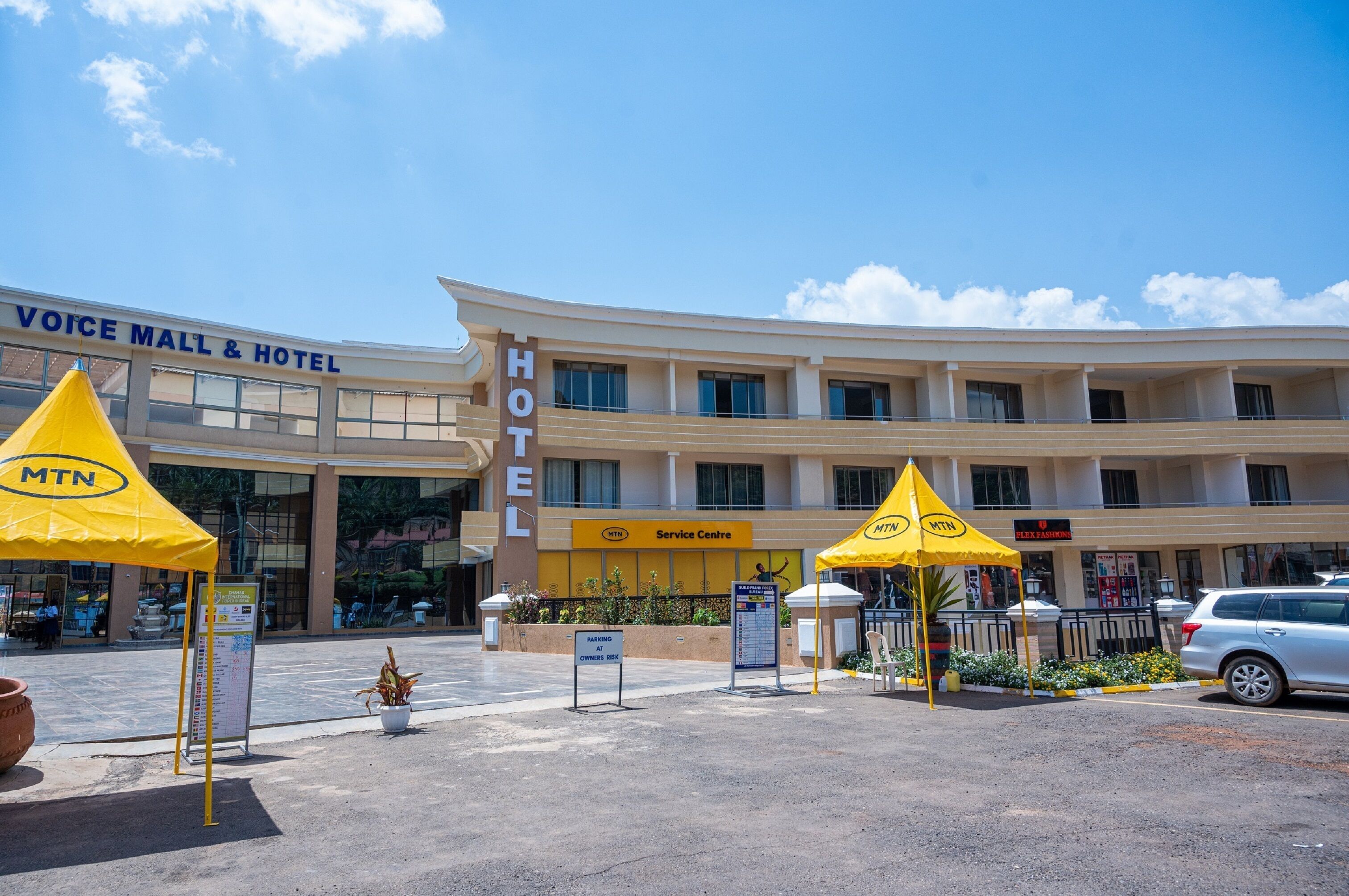 A hotel with a service center, multiple floors, and a parking area with yellow canopies.