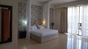 Um quarto espaçoso com uma cama grande, uma mesa de cabeceira, uma luminária na parede e um ventilador de teto.