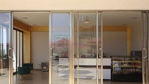 Um interior moderno com uma mesa de recepção, portas de vidro e uma área de estar com cadeiras.