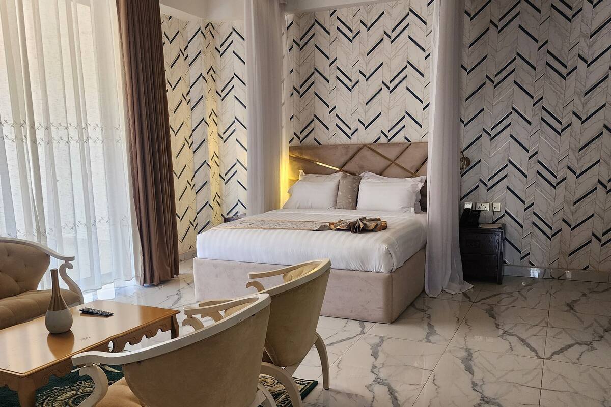 Una habitación de hotel con una cama, dos sillas, una mesita y una mesita de noche.
