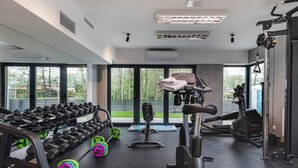A gym with various exercise equipment, large windows, and an air conditioning unit. - Comfortable Apartment | Jacuzzi, Sauna and Gym in the Building (Miedzywodzie)