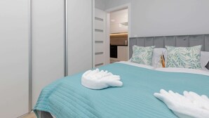 A modern bedroom with a bed, white towels, and a teal bedspread. - Comfortable Apartment | Jacuzzi, Sauna and Gym in the Building (Miedzywodzie)