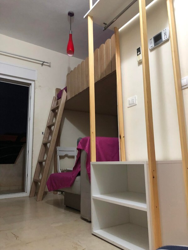 A bunk bed room with a ladder, a red hanging light, and a white wall with a power outlet. - Studio Residence LES DUNES Kantaoui Sousse  (Hammam Sousse)