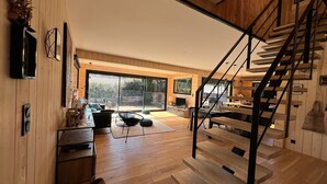 A modern interior with a wooden staircase, a dining area, and a large sliding glass door leading to an outdoor space.