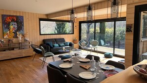A modern living space with a dining area, large windows, and a painting on the wall.