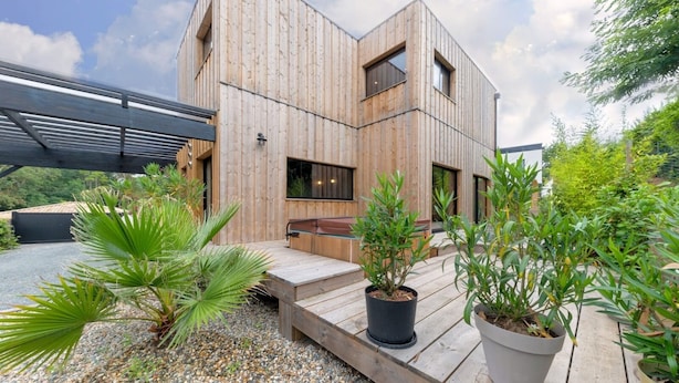 A modern wooden building with a deck and potted plants.