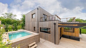 A modern wooden house with a pool, outdoor seating, and a deck.