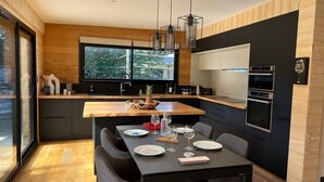 A modern kitchen with a wooden countertop, built-in appliances, and a large window.
