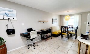 Un salon moderne comprenant un bureau, un fauteuil de bureau, un canapé et une table à manger.