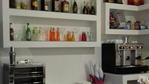 A kitchen with shelves stocked with various beverages, a coffee machine, and a microwave. - le pinède vistamare (Pozzuoli)