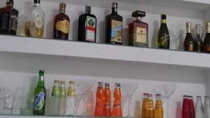 A bar area with multiple shelves stocked with various bottles of alcohol and glasses. - le pinède vistamare (Pozzuoli)